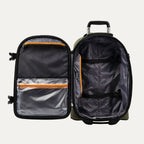 interior view of the open olive black bold by travelpro carry-on expandable rollaboard suitcase showing a spacious main compartment with two adjustable hold-down straps, a large zippered mesh lid pocket, and a clear plastic wet pocket, all highlighted by vibrant orange zipper trim.
