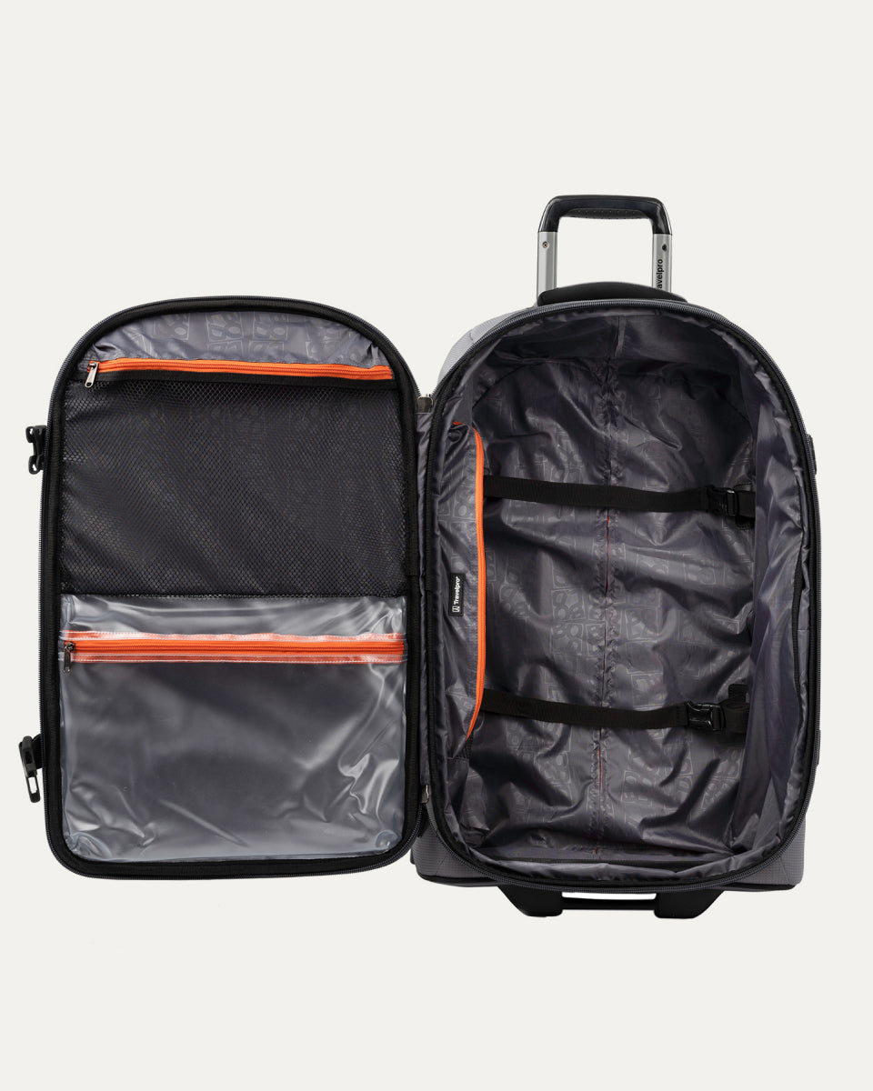 interior view of the open gray black bold by travelpro medium check-in expandable rollaboard suitcase showing a spacious main compartment with two adjustable hold-down straps and a large zippered mesh lid pocket alongside a clear plastic wet pocket with orange zipper trim.