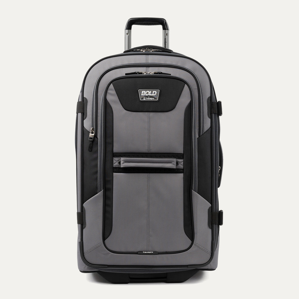 front view of the gray black bold by travelpro large check-in expandable rollaboard suitcase standing upright, showcasing its rugged black and gray polyester exterior, spacious front zippered pocket, sturdy rubberized carry handle, and extended telescoping aircraft-grade handle.