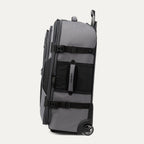 side view of the gray black bold by travelpro large check-in expandable rollaboard suitcase standing vertically, showing its durable gray fabric accent panels, side carry handle, exterior compression straps with buckles, and the extended telescoping handle.