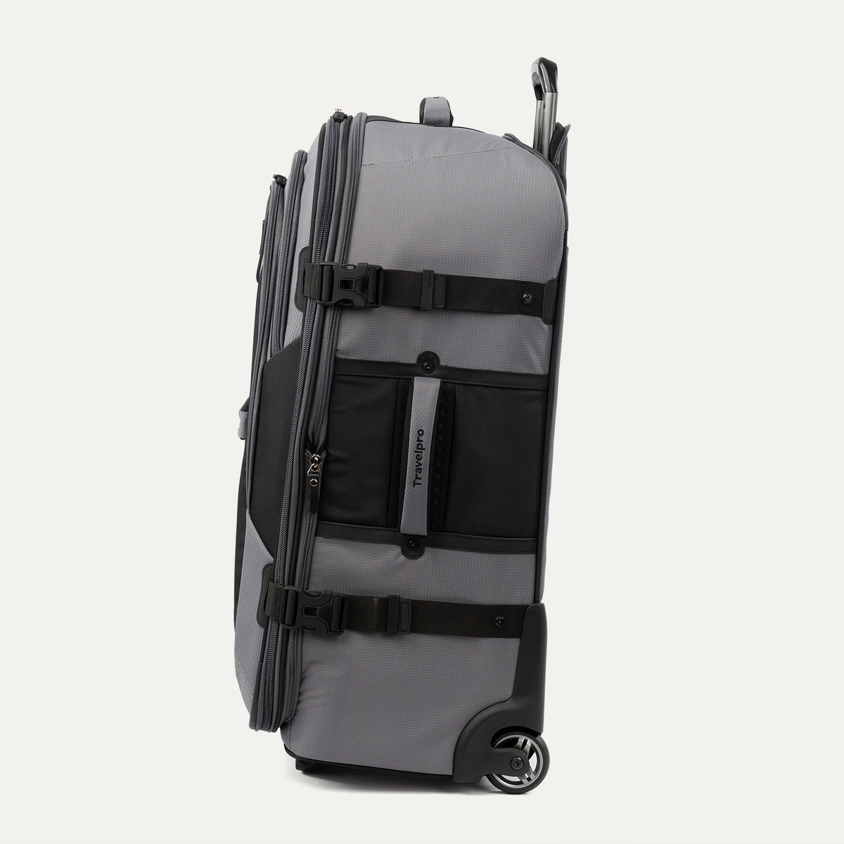 side view of the gray black bold by travelpro large check-in expandable rollaboard suitcase standing vertically, showing its durable gray fabric accent panels, side carry handle, exterior compression straps with buckles, and the extended telescoping handle.