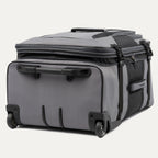 low-angle rear view of the gray black bold by travelpro large check-in expandable rollaboard suitcase resting horizontally, showcasing its two high-performance ball-bearing wheels, heavy-duty skid guards, and the molded housing around the retracted telescoping handle.