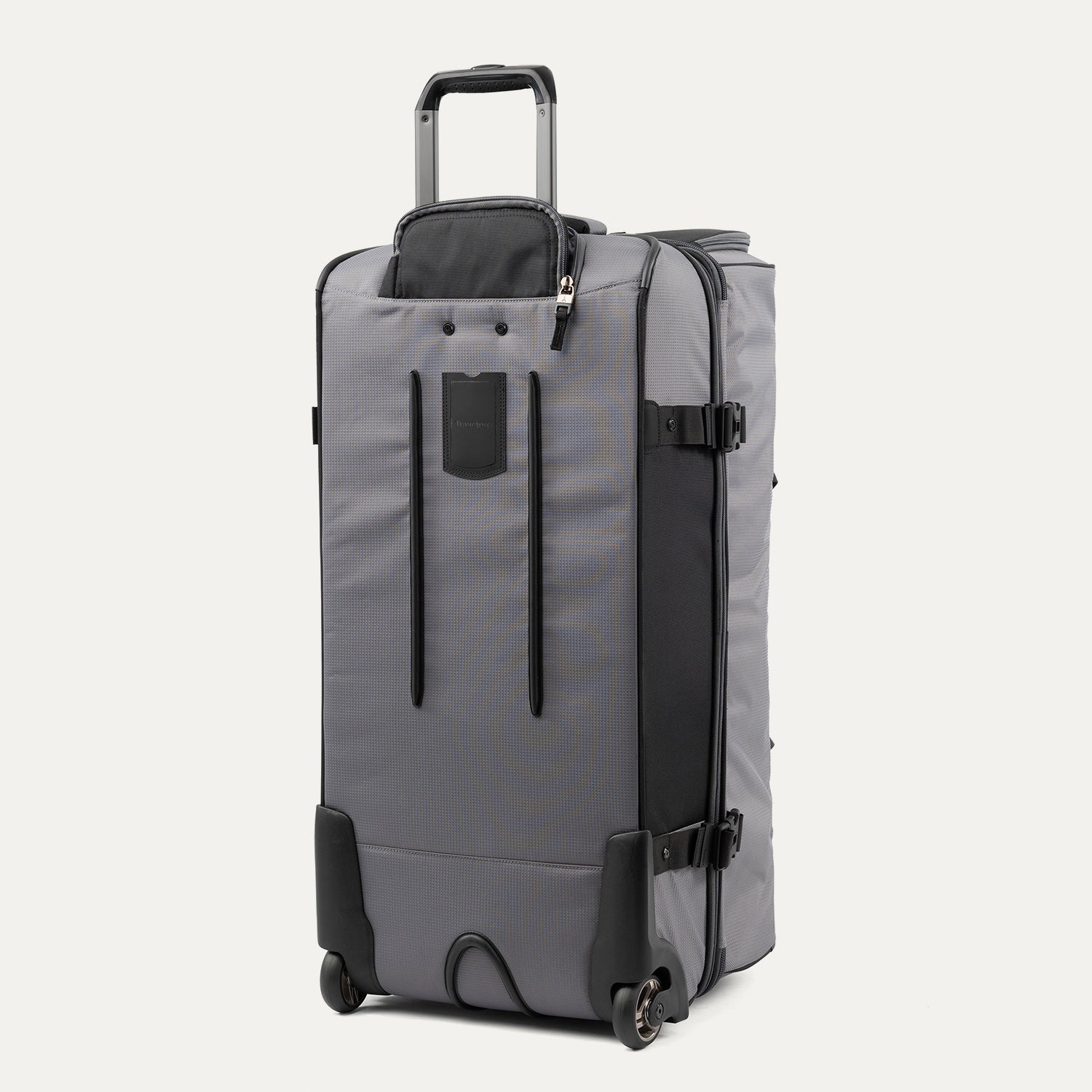 rear view of the gray black bold by travelpro large check-in drop-bottom rolling duffel bag standing vertically, showing its protective skid guards, reinforced wheel housings, two high-performance ball-bearing wheels, and extended telescoping handle.