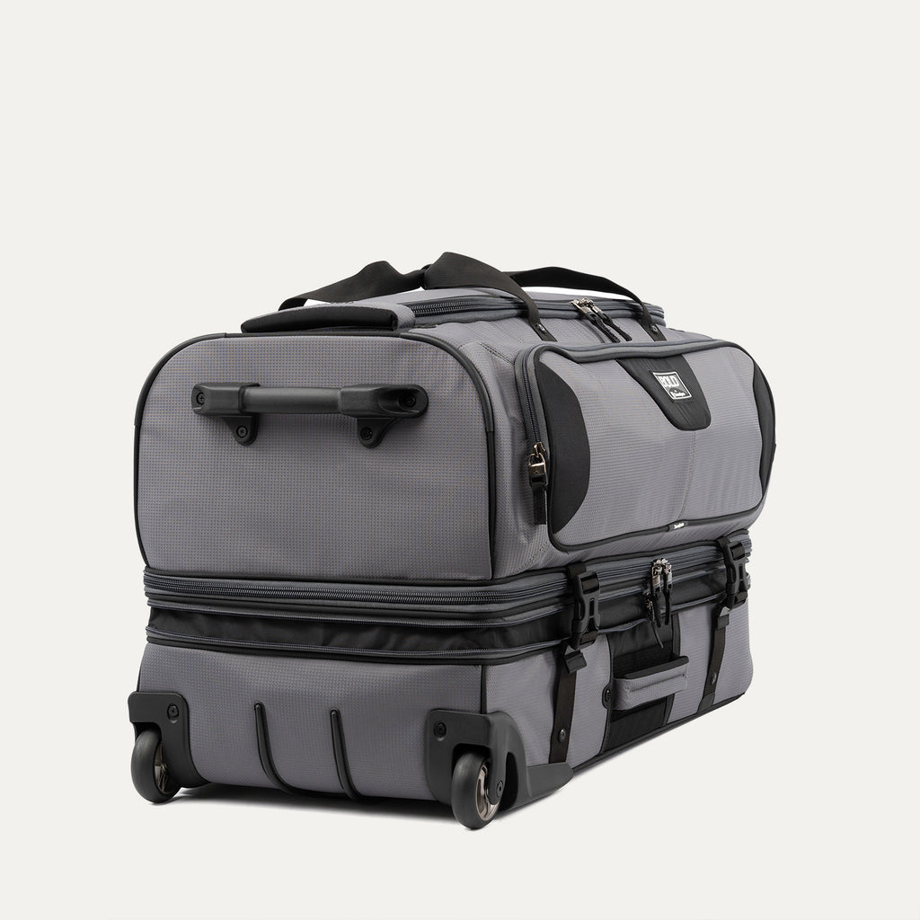 low-angle rear view of the gray black bold by travelpro large check-in drop-bottom rolling duffel bag resting horizontally, showcasing its two high-performance wheels, heavy-duty bottom skid guards, and the retracted telescoping handle base.