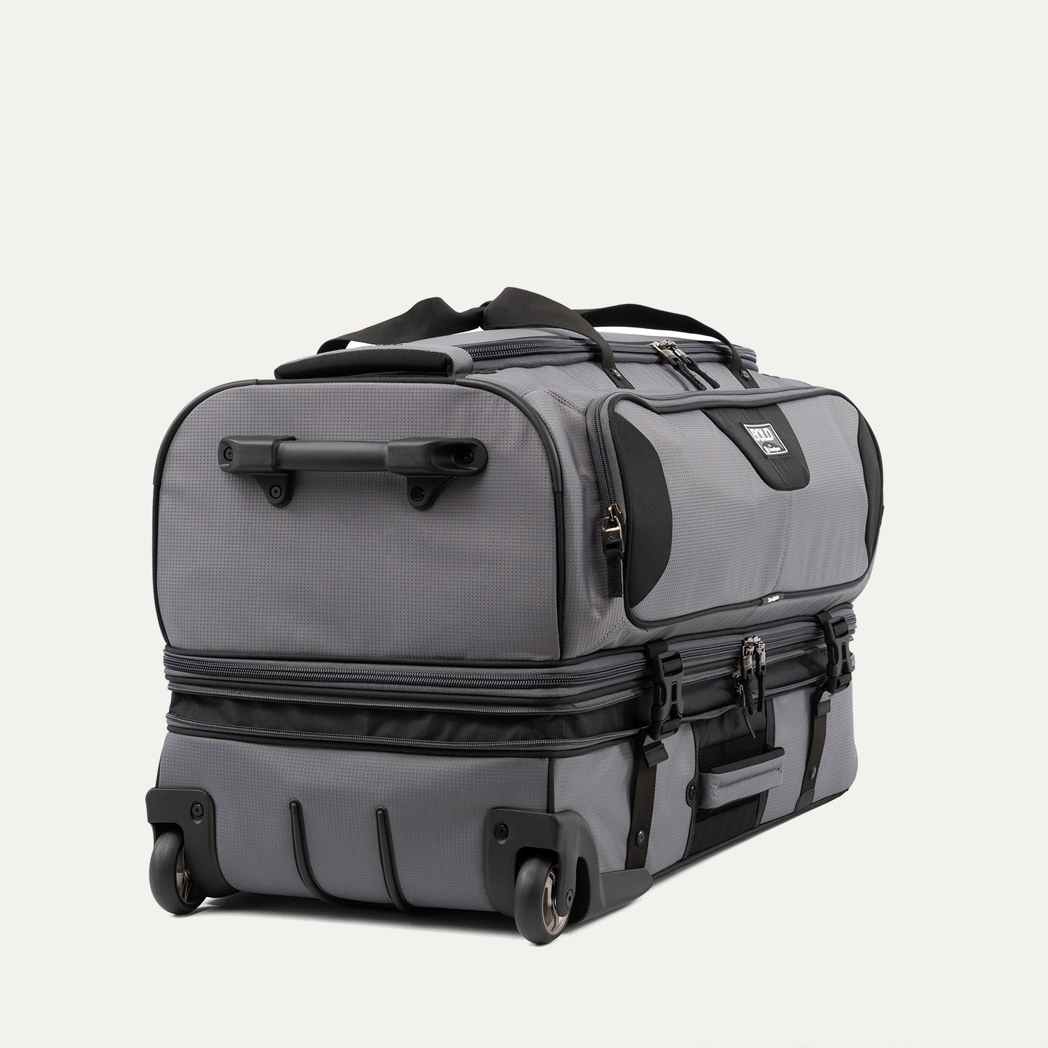low-angle rear view of the gray black bold by travelpro large check-in drop-bottom rolling duffel bag resting horizontally, showcasing its two high-performance wheels, heavy-duty bottom skid guards, and the retracted telescoping handle base.