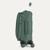 Side view of Travelpro VersaPack®+ Compact Carry-On Spinner in Desert Sage Green, featuring an expandable zipper, TSA-approved lock, and padded side carry handle with extended handle.