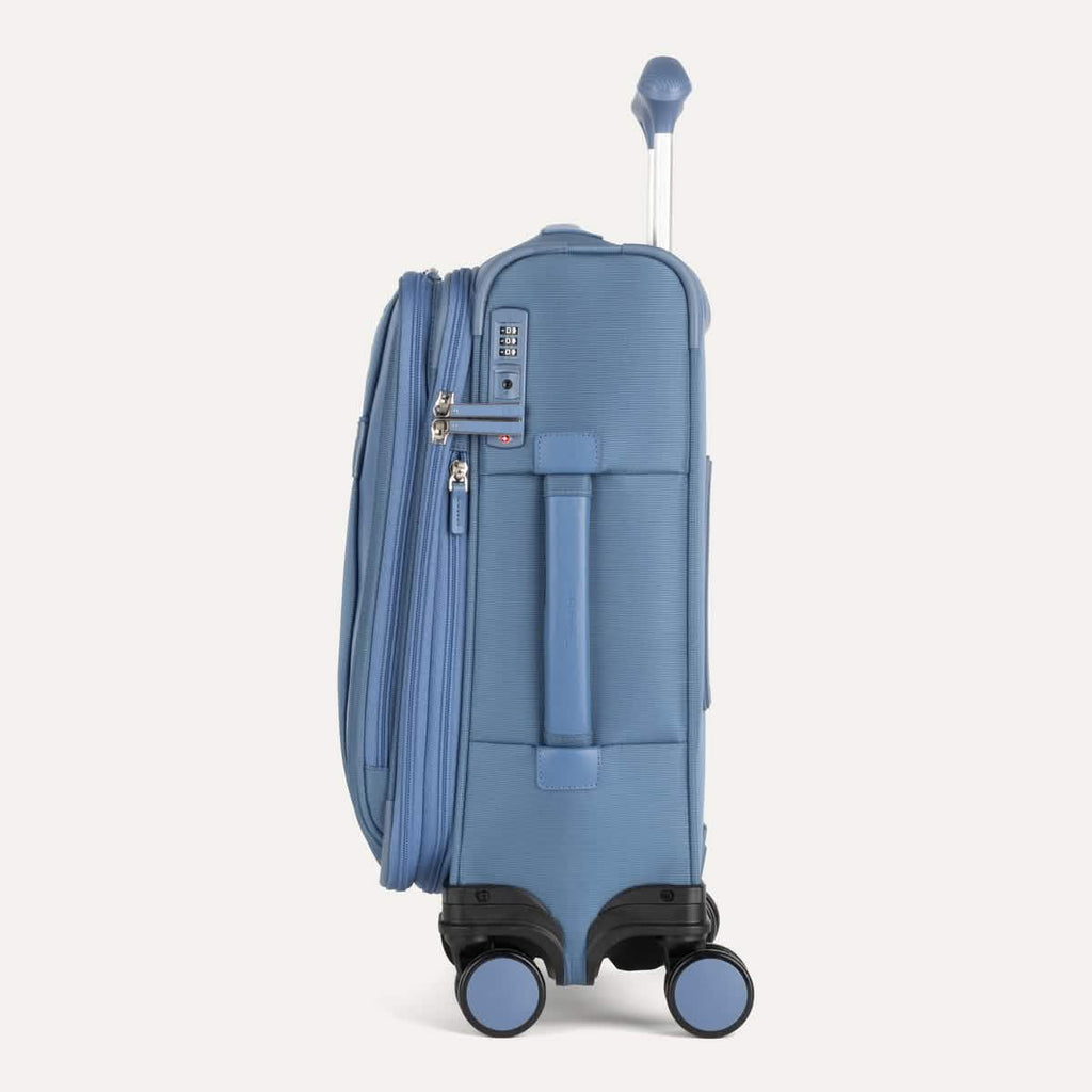 Side view of Travelpro VersaPack®+ Compact Carry-On Spinner in Elemental Blue, featuring an expandable zipper, TSA-approved lock, and padded side carry handle with extended handle.