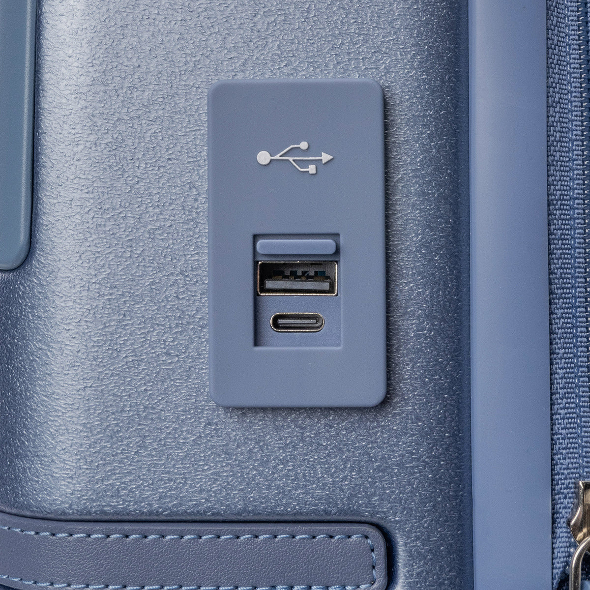 Close-up of the external USB-A and USB-C charging ports on the Travelpro Platinum Reserve Compact Carry-On Hardside Spinner in Steel Blue