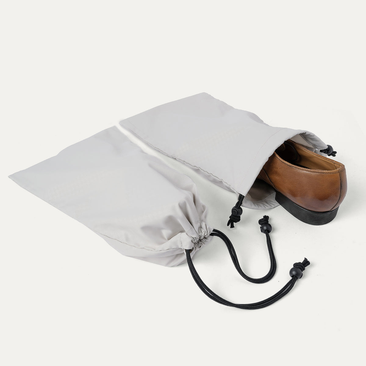 Drawstring shoe bag included with the Travelpro Platinum Reserve Compact Carry-On Hardside Spinner in Midnight Trail, shown holding a pair of shoes