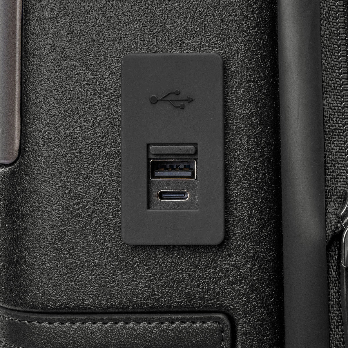 Close-up of the external USB-A and USB-C charging ports on the Travelpro Platinum Reserve Carry-On Hardside Spinner in Black Dust
