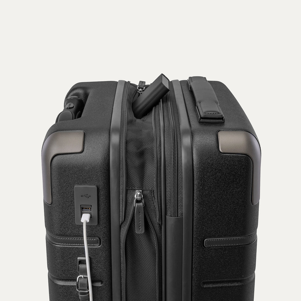 Charging cable plugged into the external USB port on the Travelpro Platinum Reserve Carry-On Hardside Spinner in Black Dust