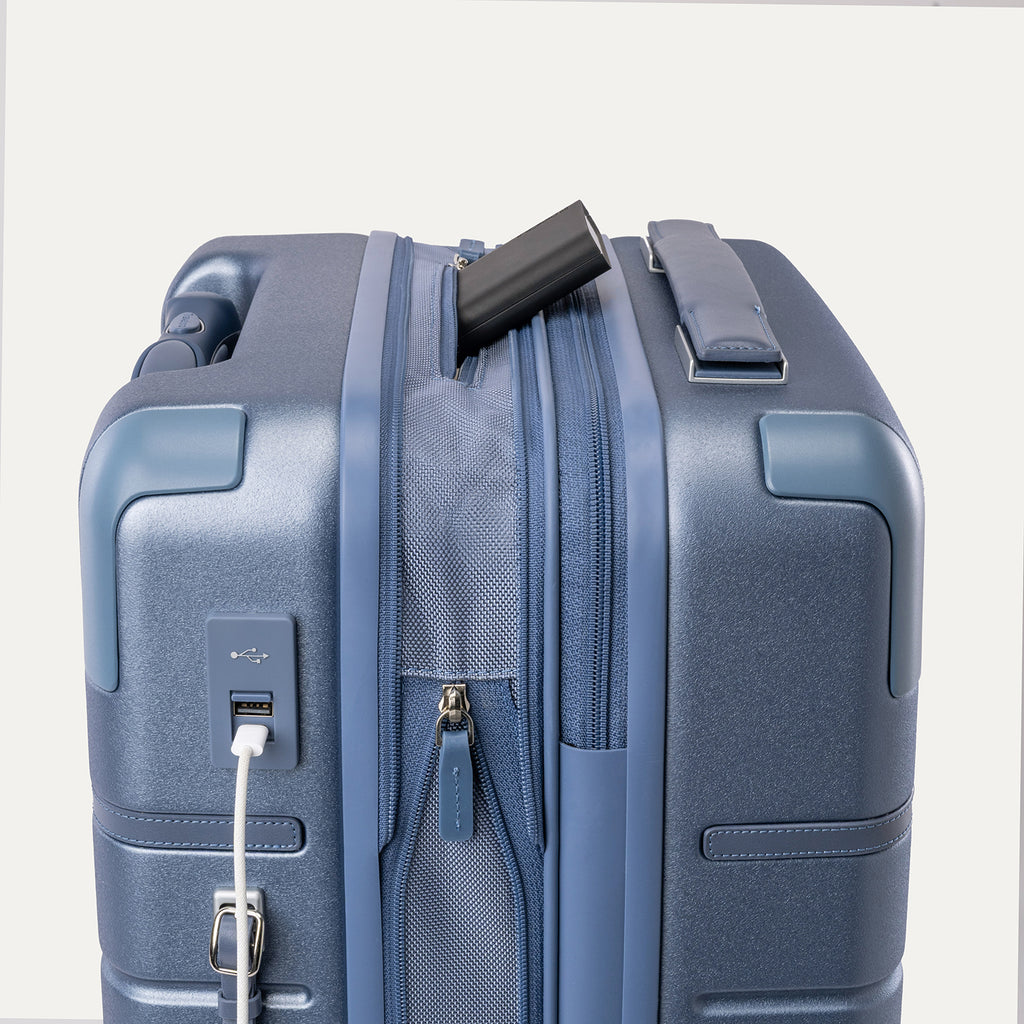 Charging cable plugged into the external USB port on the Travelpro Platinum Reserve Carry-On Hardside Spinner in Steel Blue