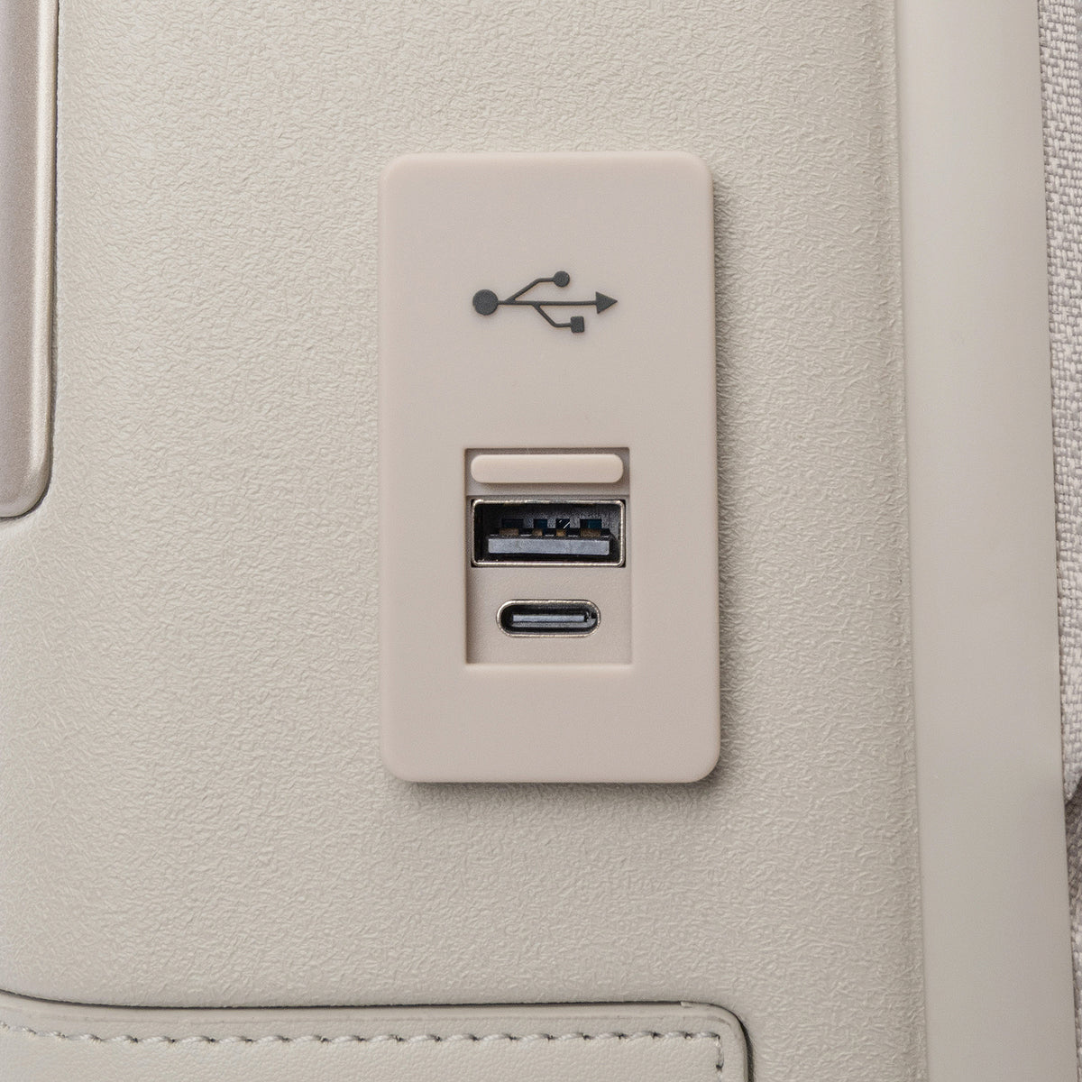 Close-up of the external USB-A and USB-C charging ports on the Travelpro Platinum Reserve Carry-On Hardside Spinner in Sandstone
