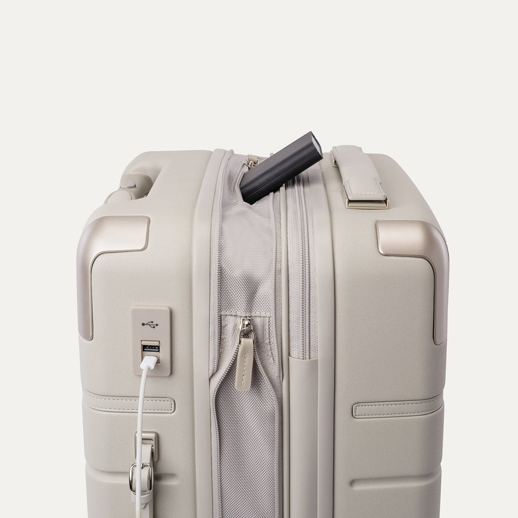 Charging cable plugged into the external USB port on the Travelpro Platinum Reserve Carry-On Hardside Spinner in Sandstone