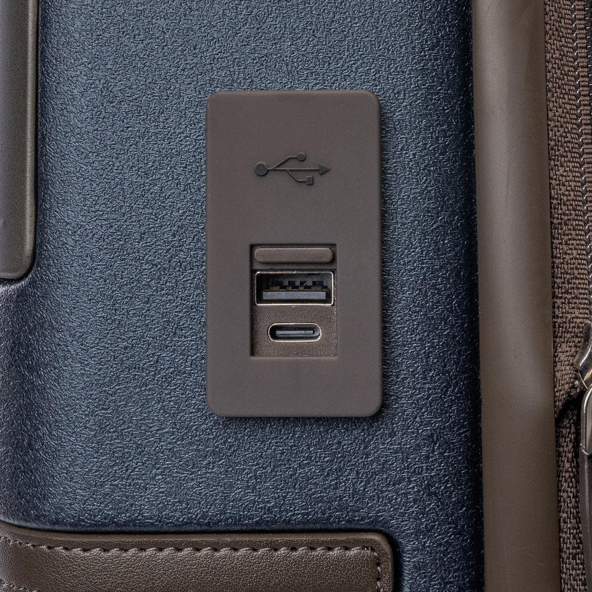 Close-up of the external USB-A and USB-C charging ports on the Travelpro Platinum Reserve Carry-On Hardside Spinner in Midnight Trail