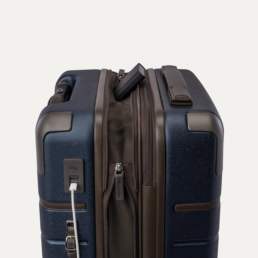 Charging cable plugged into the external USB port on the Travelpro Platinum Reserve Carry-On Hardside Spinner in Midnight Trail