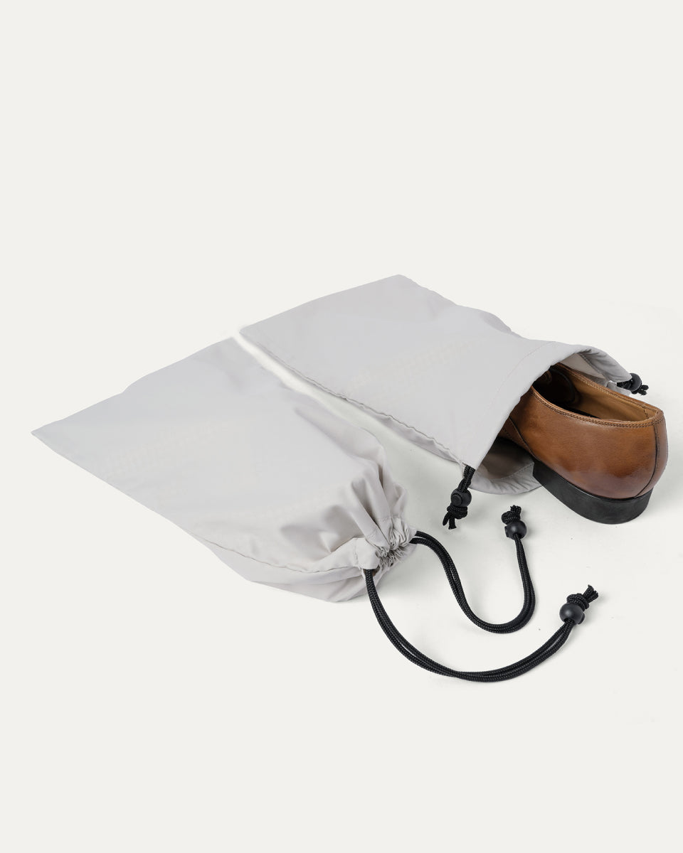 Drawstring shoe bag included with the Travelpro Platinum Reserve Carry-On Hardside Spinner in Midnight Trail, shown holding a pair of shoes