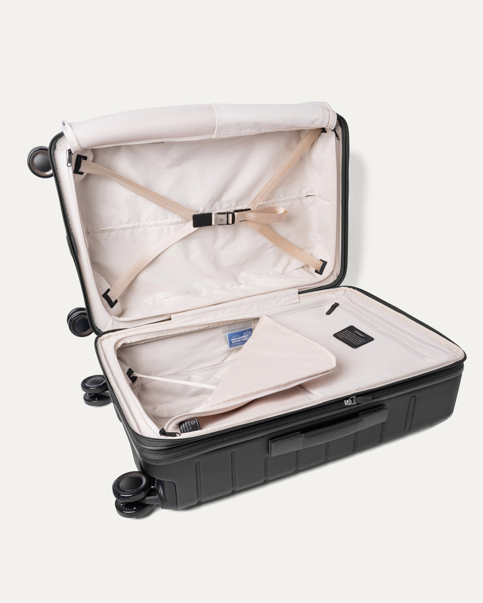 Open interior of the Travelpro Platinum Reserve Medium Check-In Hardside Spinner in Black Dust with hold-down straps