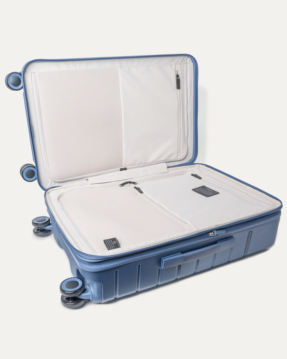 Open interior of the Travelpro Platinum Reserve Medium Check-In Hardside Spinner in Steel Blue showing the zippered divider panel and dedicated pockets
