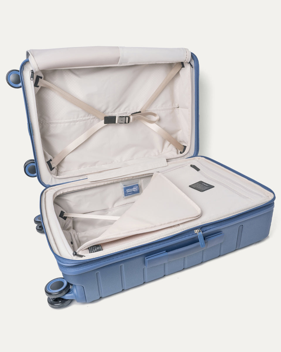 Open interior of the Travelpro Platinum Reserve Medium Check-In Hardside Spinner in Steel Blue with hold-down straps