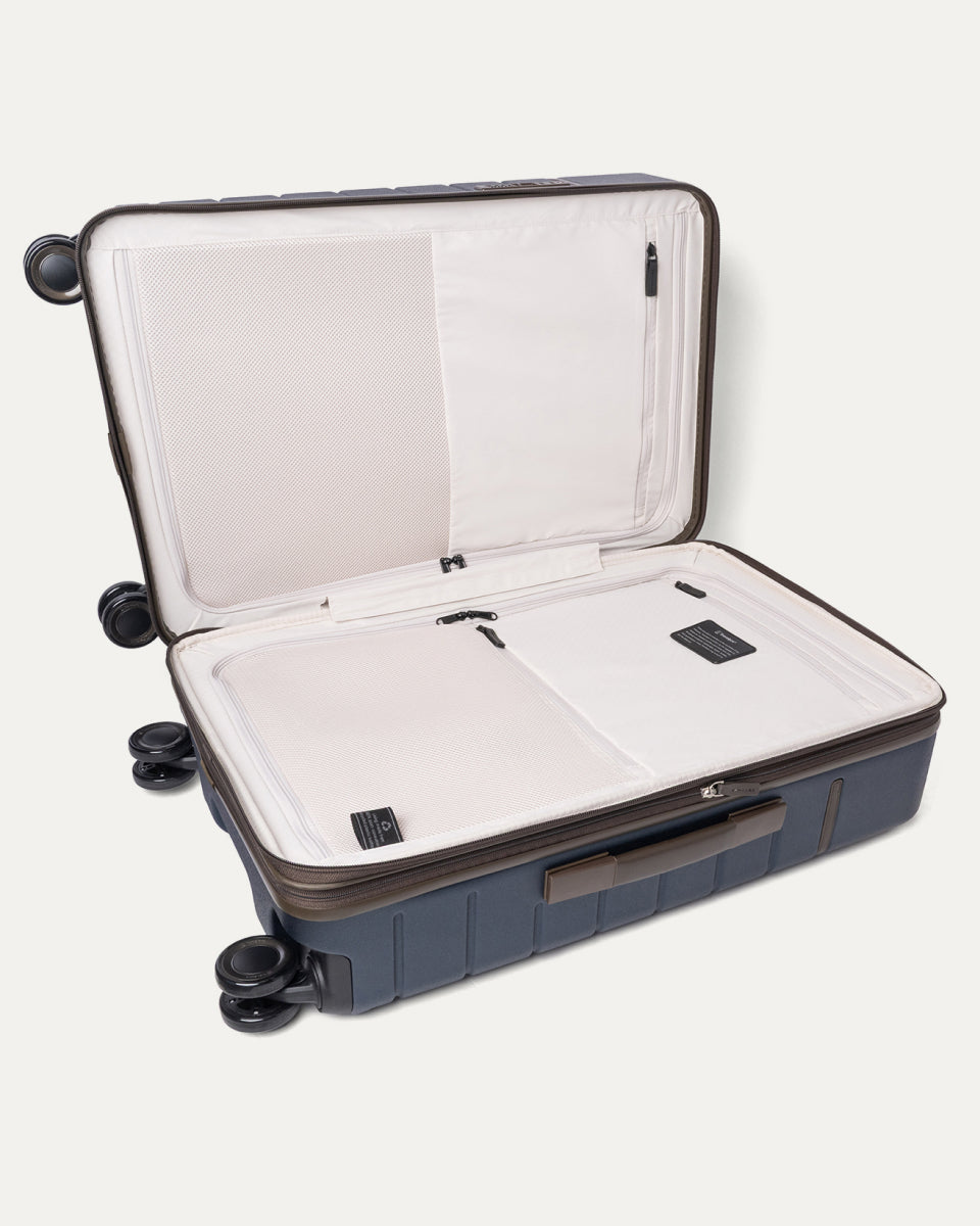 Open interior of the Travelpro Platinum Reserve Medium Check-In Hardside Spinner in Midnight Trail showing the zippered divider panel and dedicated pockets