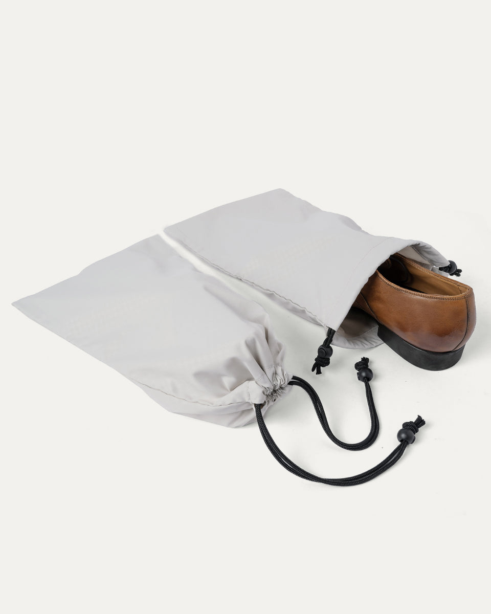 Drawstring shoe bag included with the Travelpro Platinum Reserve Large Check-In Hardside Spinner in Steel Blue, shown holding a pair of shoes