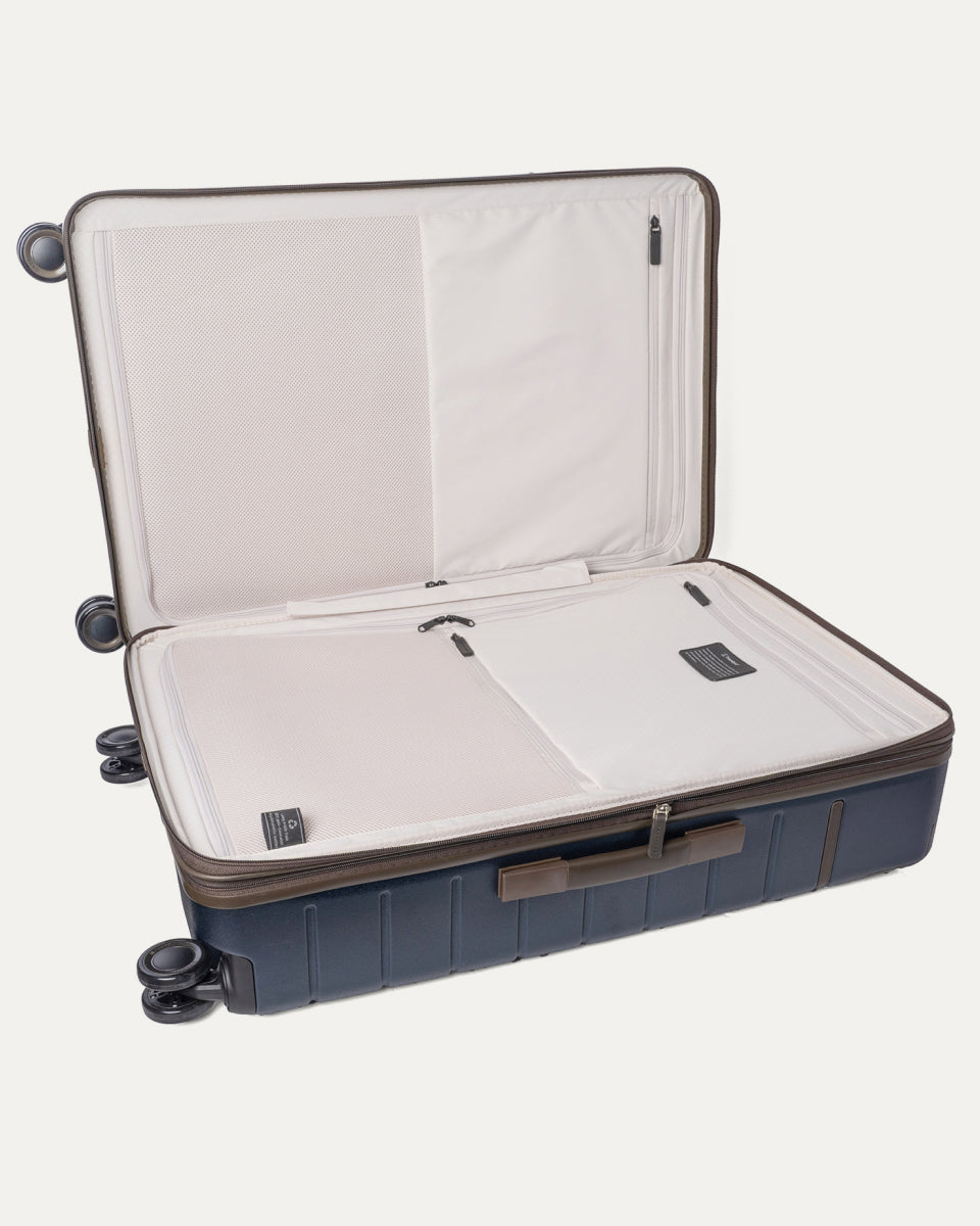 Open interior of the Travelpro Platinum Reserve Large Check-In Hardside Spinner in Midnight Trail showing the zippered divider panel and dedicated pockets