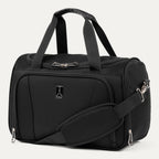Three-quarter front view of the Travelpro Runway Tote in Black, showing dual top grab handles, an adjustable shoulder strap with a padded shoulder wrap, a front zippered compartment with the Travelpro logo badge, and silver hardware against a clean off-white background.