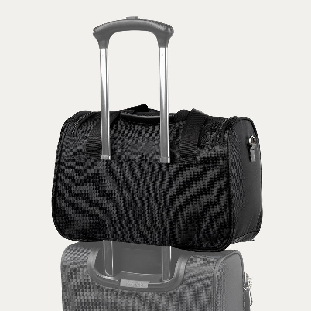 Rear view of the black Travelpro Runway Tote stacked on the telescopic handle of a matching spinner suitcase, showing the rear luggage sleeve against an off-white background.