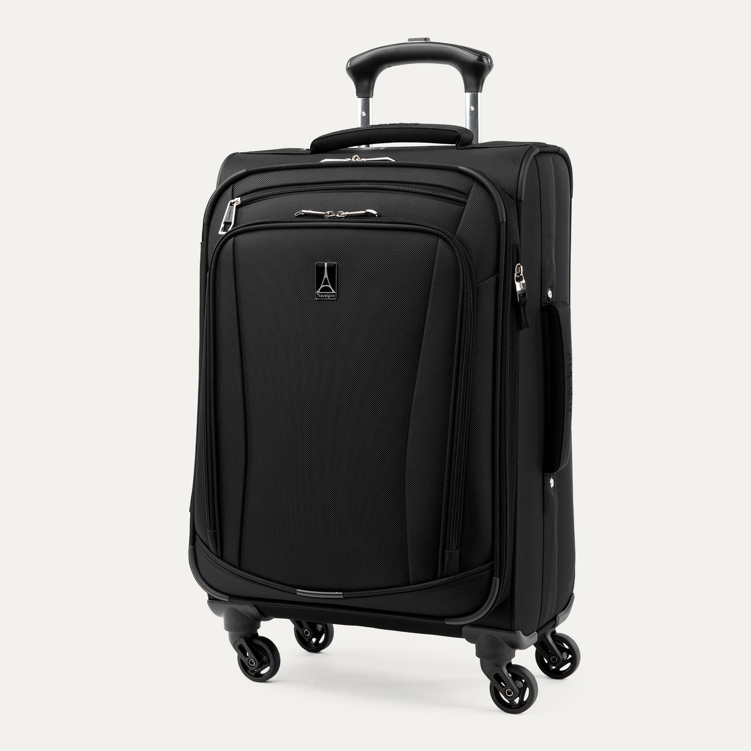 Three-quarter front view of the Travelpro Runway Tote / Carry-on Luggage Set in Black, showcasing the softside carry-on spinner featuring an extended telescopic handle, a zippered front pocket with the Travelpro logo badge, and multi-directional spinner wheels against a clean off-white background.