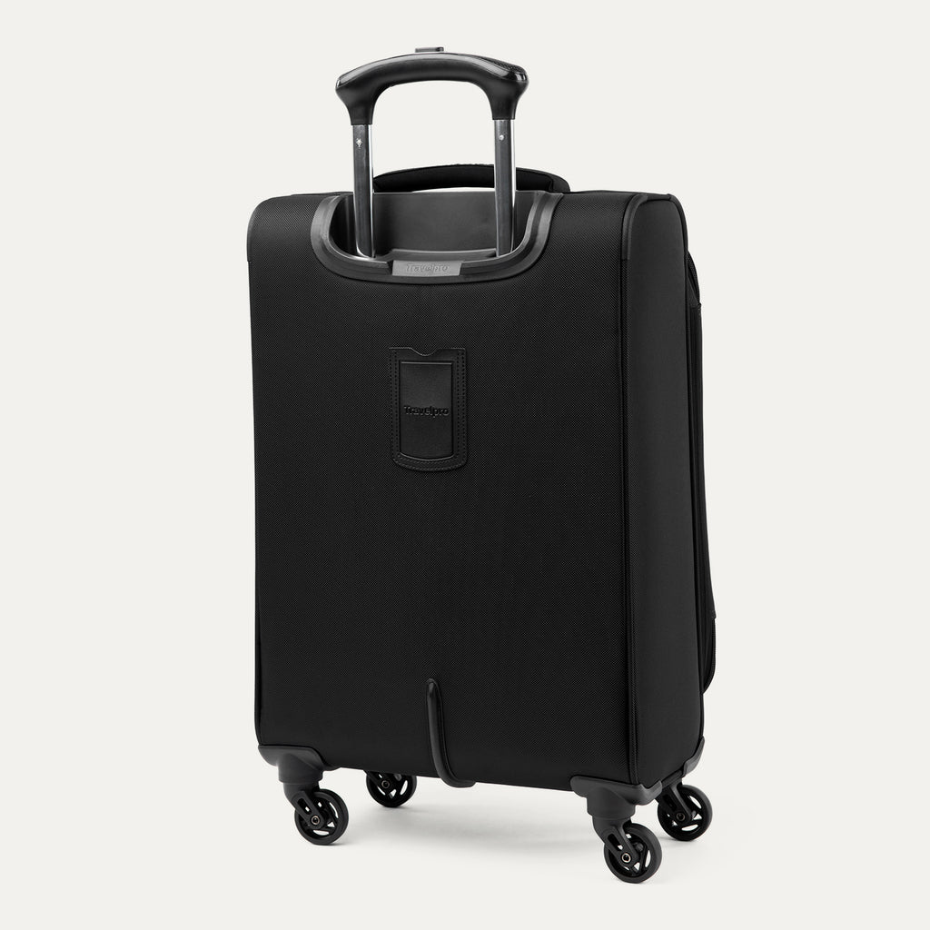 Three-quarter rear view of the Travelpro Runway Tote / Carry-on Luggage Set in Black, showcasing the softside carry-on spinner featuring an extended telescopic handle, a zippered front pocket with the Travelpro logo badge, and multi-directional spinner wheels against a clean off-white background.