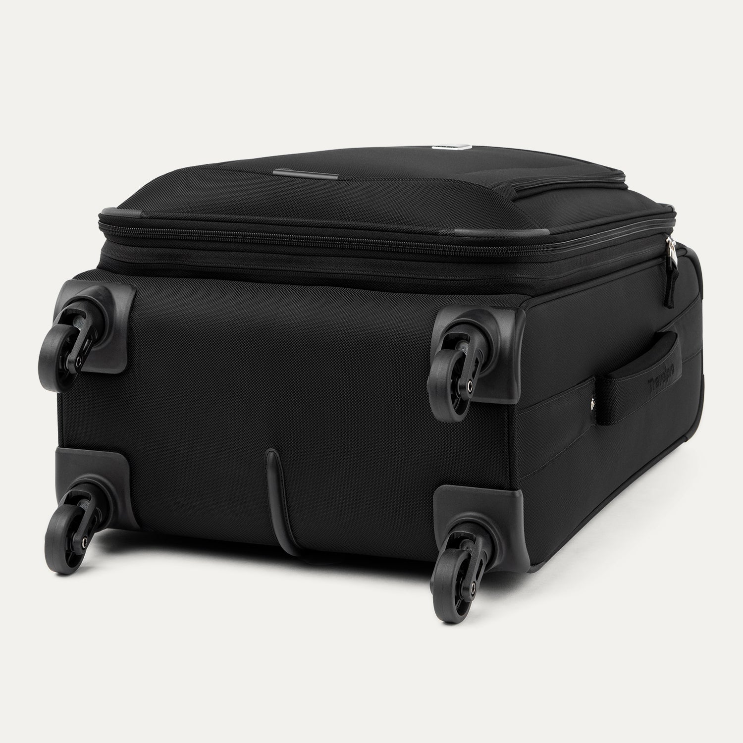 Three-quarter rear view of the Travelpro Runway Tote / Carry-on Luggage Set in Black, showing the softside carry-on spinner resting on its side wheels and corner guards against a clean off-white background.