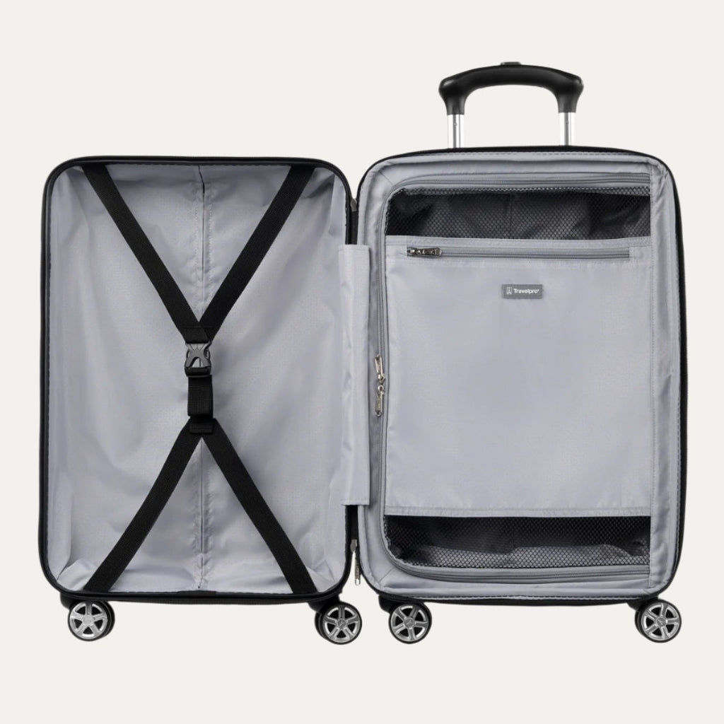 Open black hardside spinner suitcase showing interior with cross straps on one side and a zippered mesh divider pocket on the other.