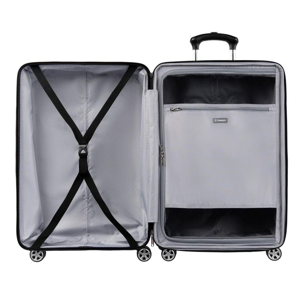 Interior view of an open large hardshell spinner suitcase, showing two compartments one with adjustable cross straps and the other with a zippered mesh divider containing an additional zip pocket.