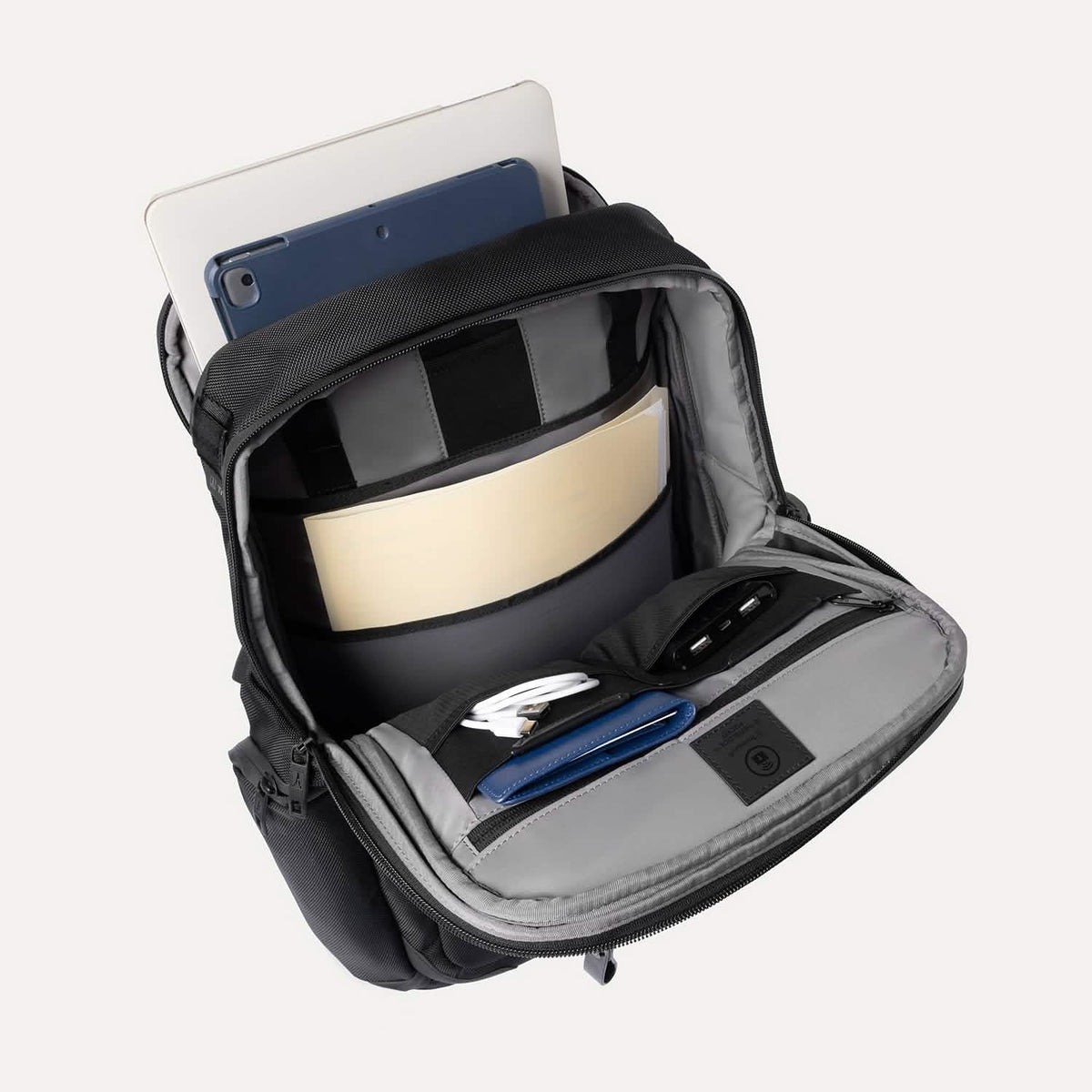 Black backpack with compartments containing electronic devices on a white background