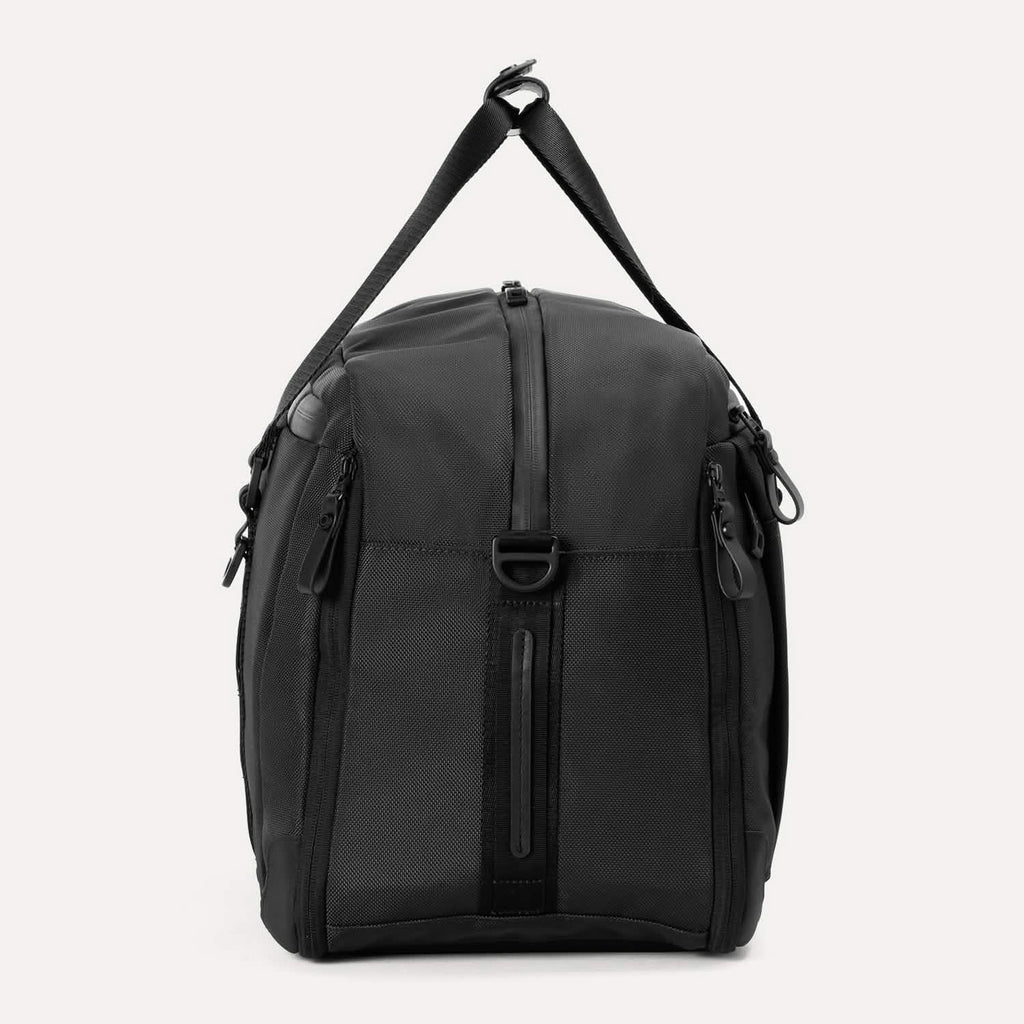 Side view of Travelpro Altitude Double Expansion Duffel in Jet Black with vertical zipper, D-ring, and adjustable strap.
