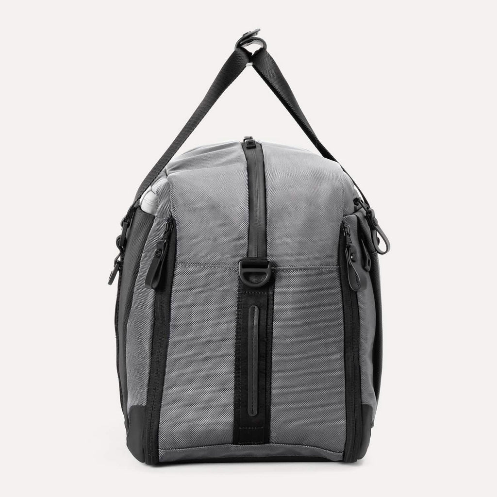 Side view of the Travelpro® Altitude™ Double Expansion Duffel in Falcon Grey, showing the vertical zippered pocket, top carry handle, and D-ring attachment point.
