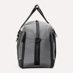 Side view of the Travelpro® Altitude™ Double Expansion Duffel in Falcon Grey, showing the vertical zippered pocket, top carry handle, and D-ring attachment point.