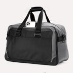 Slanted rear view of the Travelpro® Altitude™ Double Expansion Duffel in Falcon Grey, featuring a smartphone partially inserted into the top opening of the rear pocket.