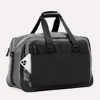  Slanted rear view of the Travelpro® Altitude™ Double Expansion Duffel in Falcon Grey, showing an exterior pocket with a smartphone partially inserted.