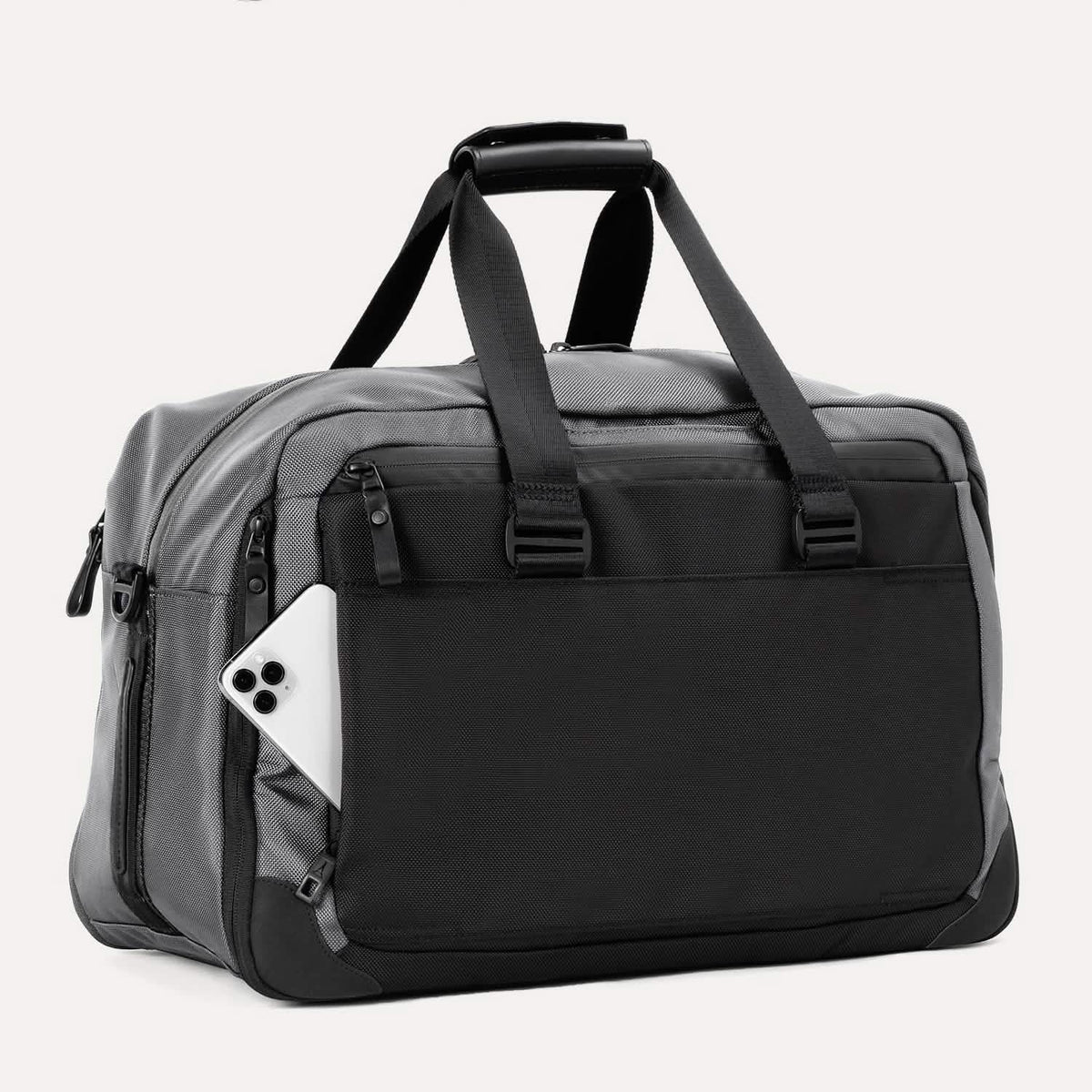  Slanted rear view of the Travelpro® Altitude™ Double Expansion Duffel in Falcon Grey, showing an exterior pocket with a smartphone partially inserted.