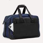 Slanted rear view of the Travelpro® Altitude™ Double Expansion Duffel in Aviator Navy/Black, featuring a quick-access pocket with a smartphone partially inserted and padded dual handles.
