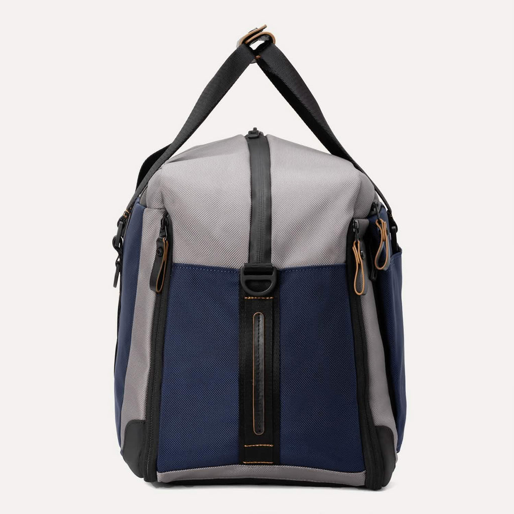 Side view of the Travelpro® Altitude™ Double Expansion Duffel in Stellar Navy/Grey, showing the side profile with zipper closures and carry handles 