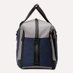 Side view of the Travelpro® Altitude™ Double Expansion Duffel in Stellar Navy/Grey, showing the side profile with zipper closures and carry handles 