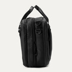 Side view of the Travelpro® Altitude™ Full Expansion Brief in black, showing dual top carry handles, expansion zippers, and D-rings for an optional shoulder strap.