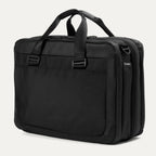 Slanted rear view of the Travelpro® Altitude™ Full Expansion Brief in black, featuring dual top carry handles and a large rear slip pocket for quick-access storage, along with side D-rings for attaching the adjustable shoulder strap.
