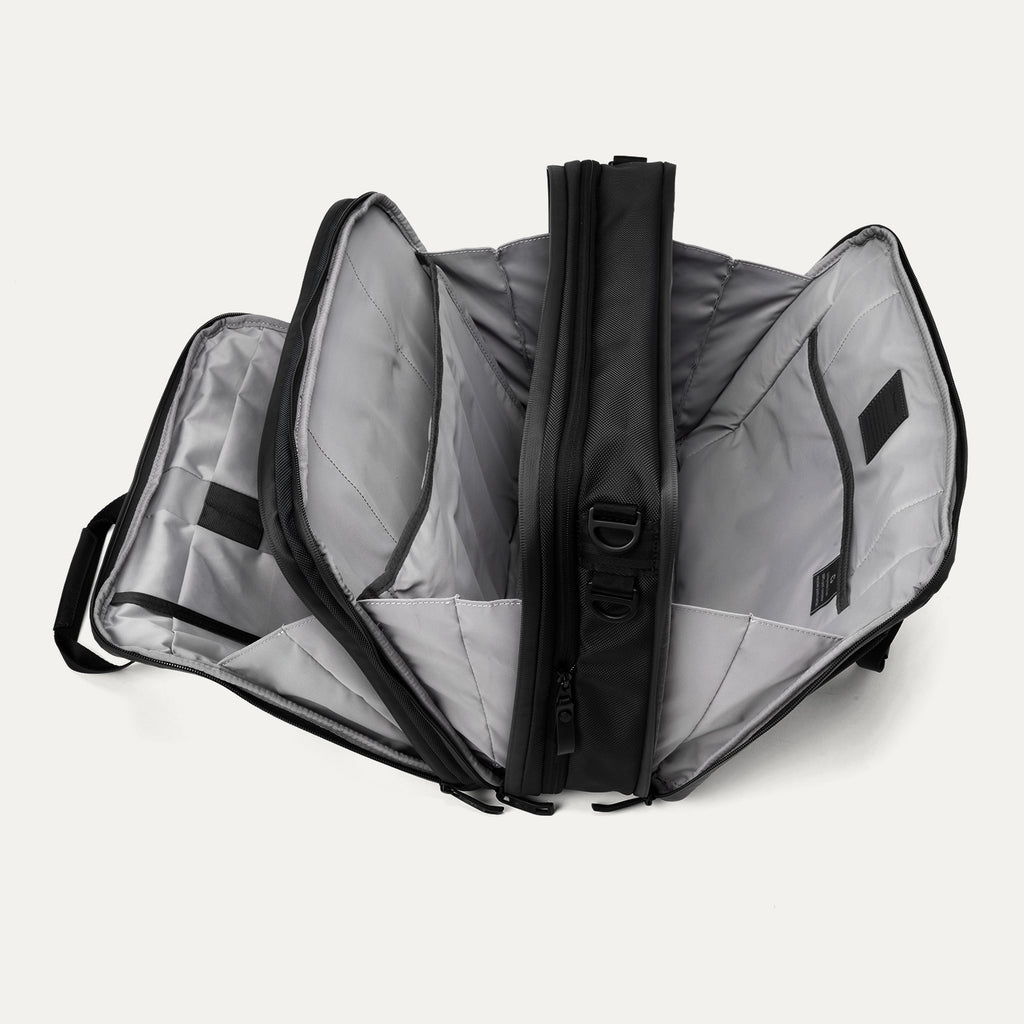 Open view of the Travelpro® Altitude™ Full Expansion Brief in black, showing three spacious compartments with divider panels and organizational sleeves.
