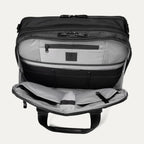 Open front pocket view of the Travelpro® Altitude™ Full Expansion Brief in black, showing an organized interior with a zippered pocket and multiple divided compartments for accessories.

