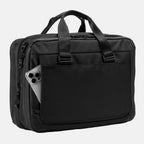 Travelpro® Altitude™ Full Expansion Brief in black, featuring dual top carry handles with reinforced stitching, vertical webbing accents for durability and style, and an easy-access rear slip pocket holding a smartphone.