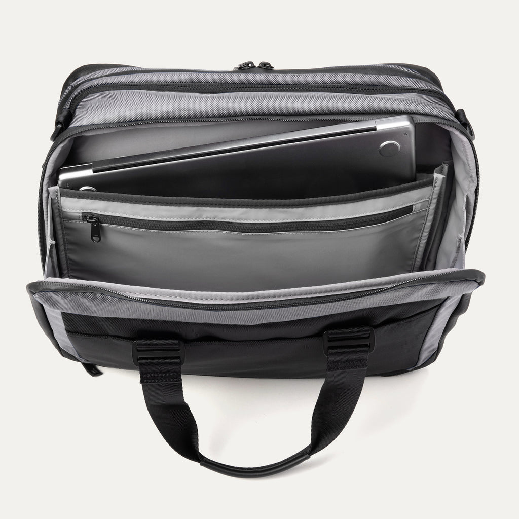 Rear compartment view of the Travelpro® Altitude™ Full Expansion Brief in Falcon Grey, showing the padded laptop sleeve holding a laptop, an additional tablet sleeve, and a zippered pocket for accessories.
